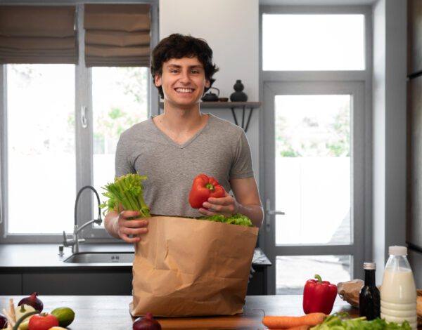 Person holding reusable grocery bag filled with fresh produce and pulses, promoting sustainable living and healthy eating.